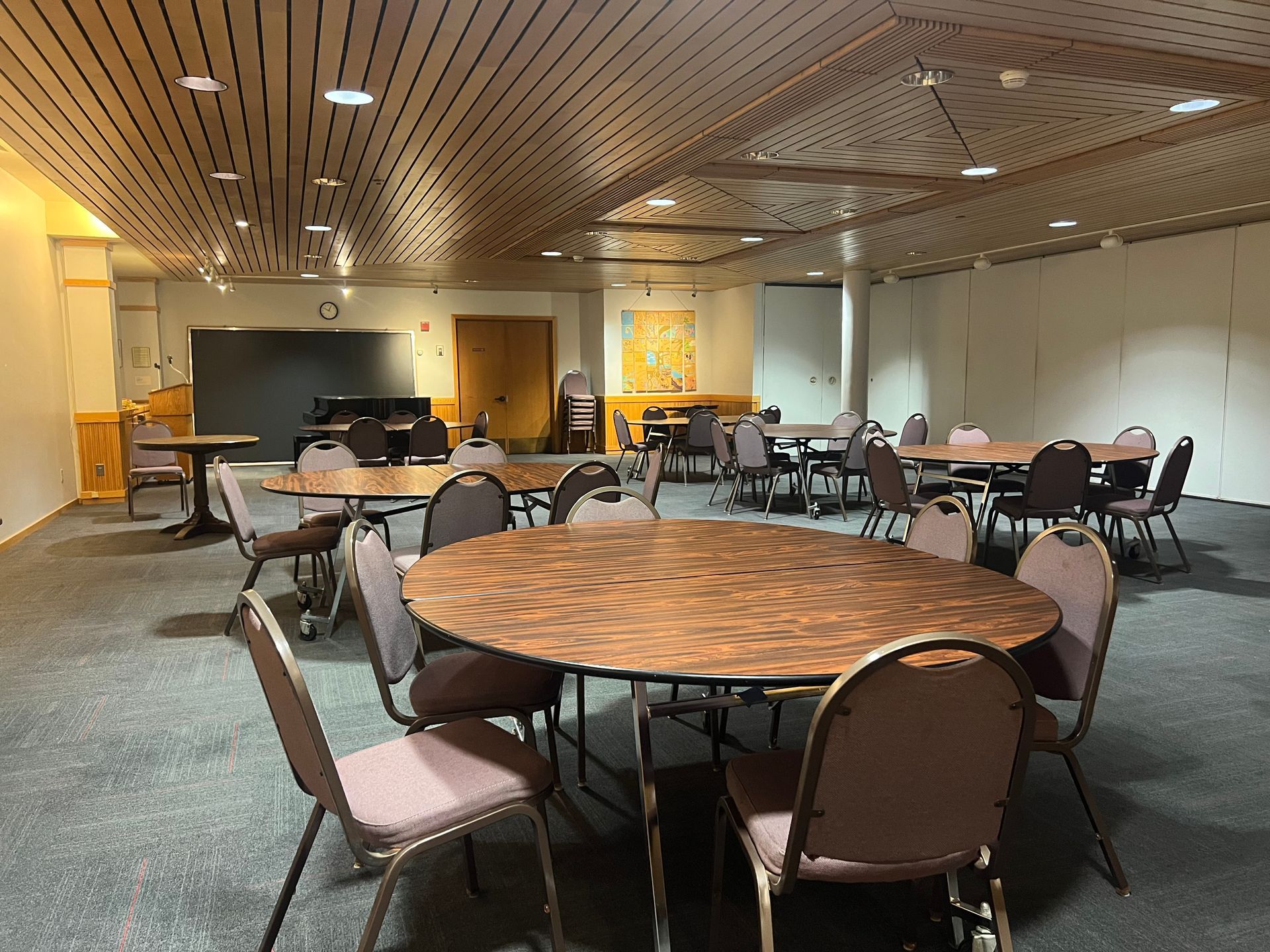 Empty conference room with round tables, chairs, and a large screen at the front