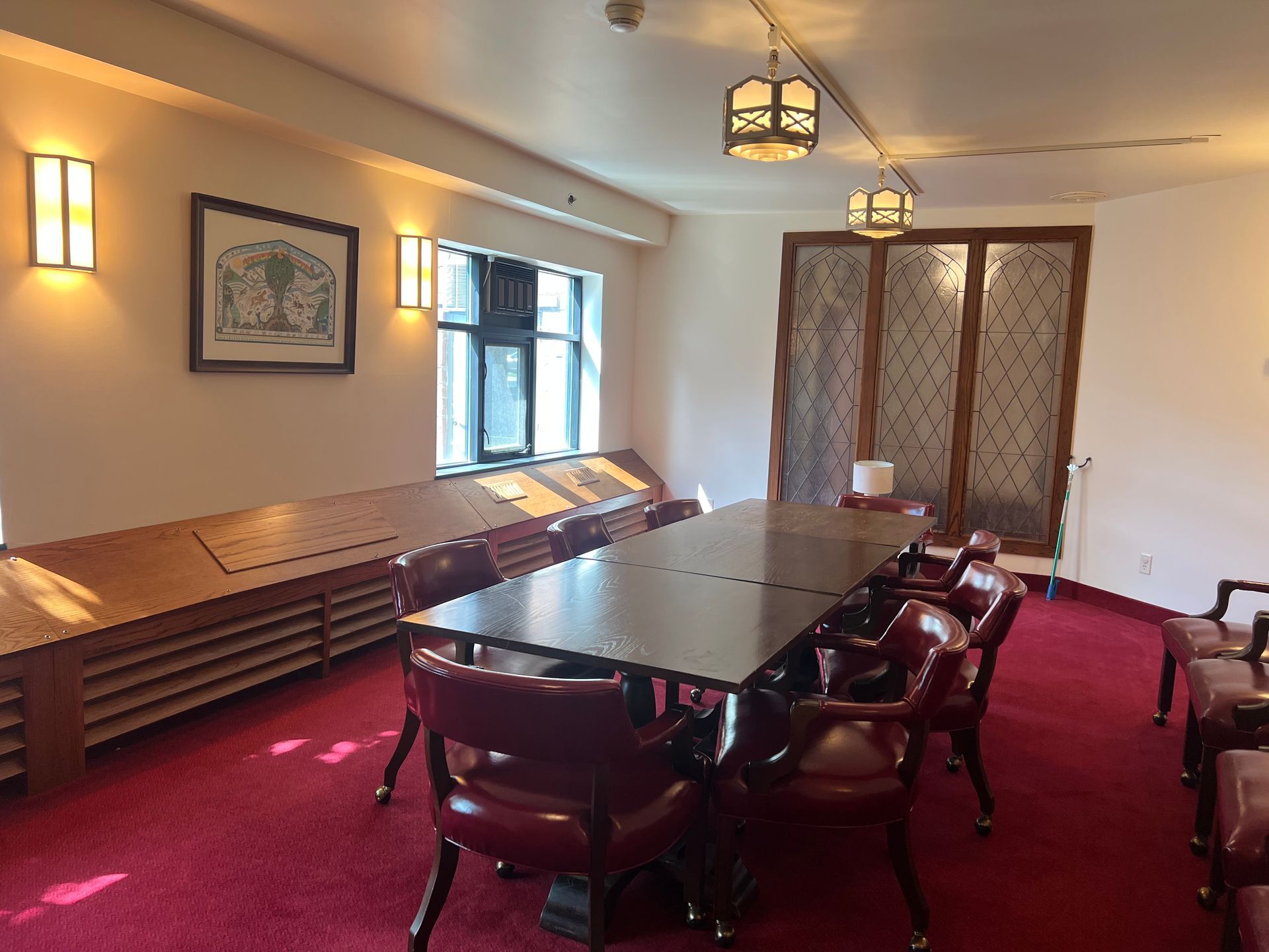 Conference room with red carpet, long table, leather chairs, wall art, and pendant lights