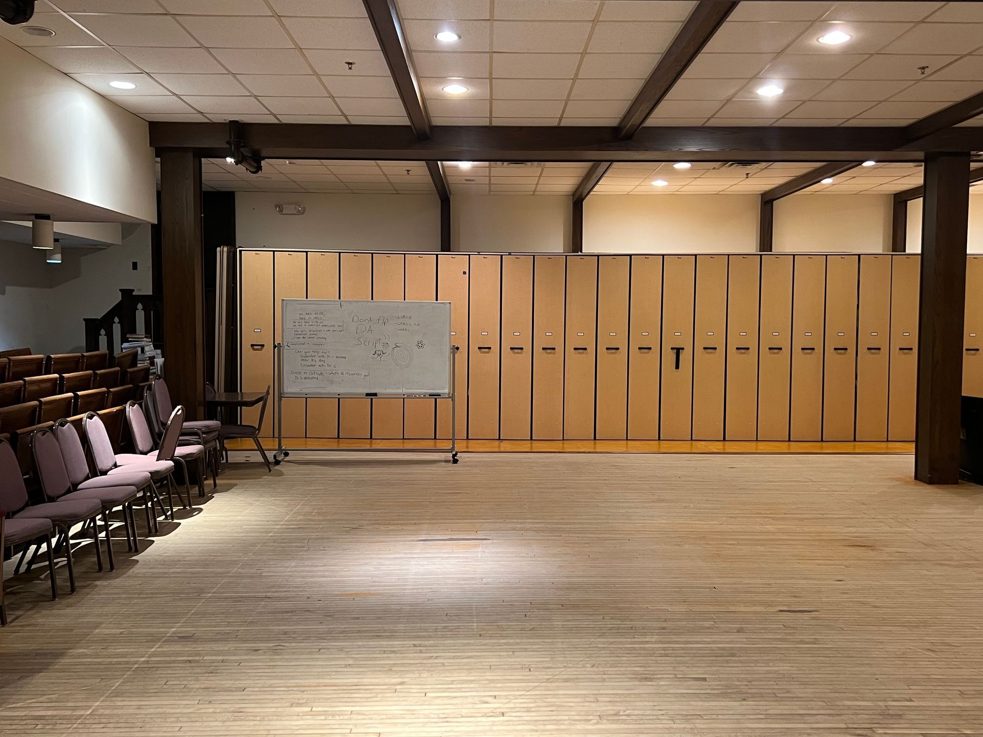 Empty conference room with rows of chairs, a whiteboard, and wood-paneled storage cabinets