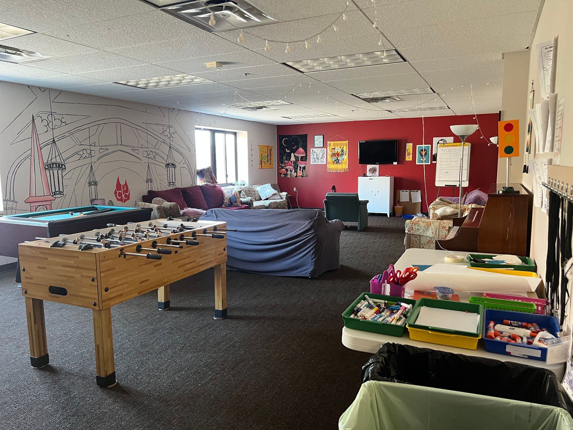 Classroom with tables, colorful wall art, and assorted supplies in a bright open space