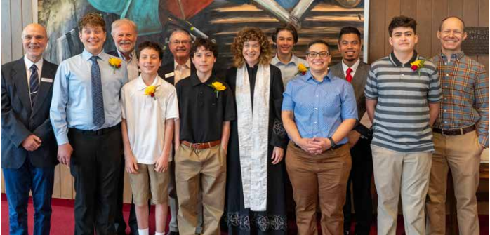 Group of people posing in front of a mural, smiling in casual shirts and business attire.