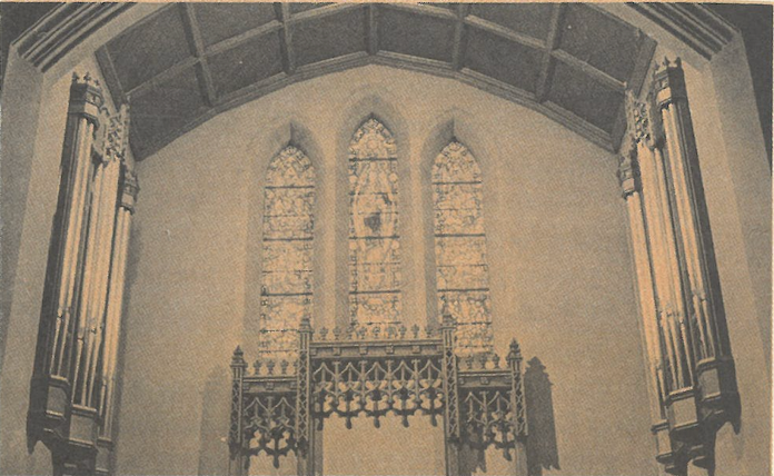 Interior of a church altar with stained-glass windows and carved wooden decoration