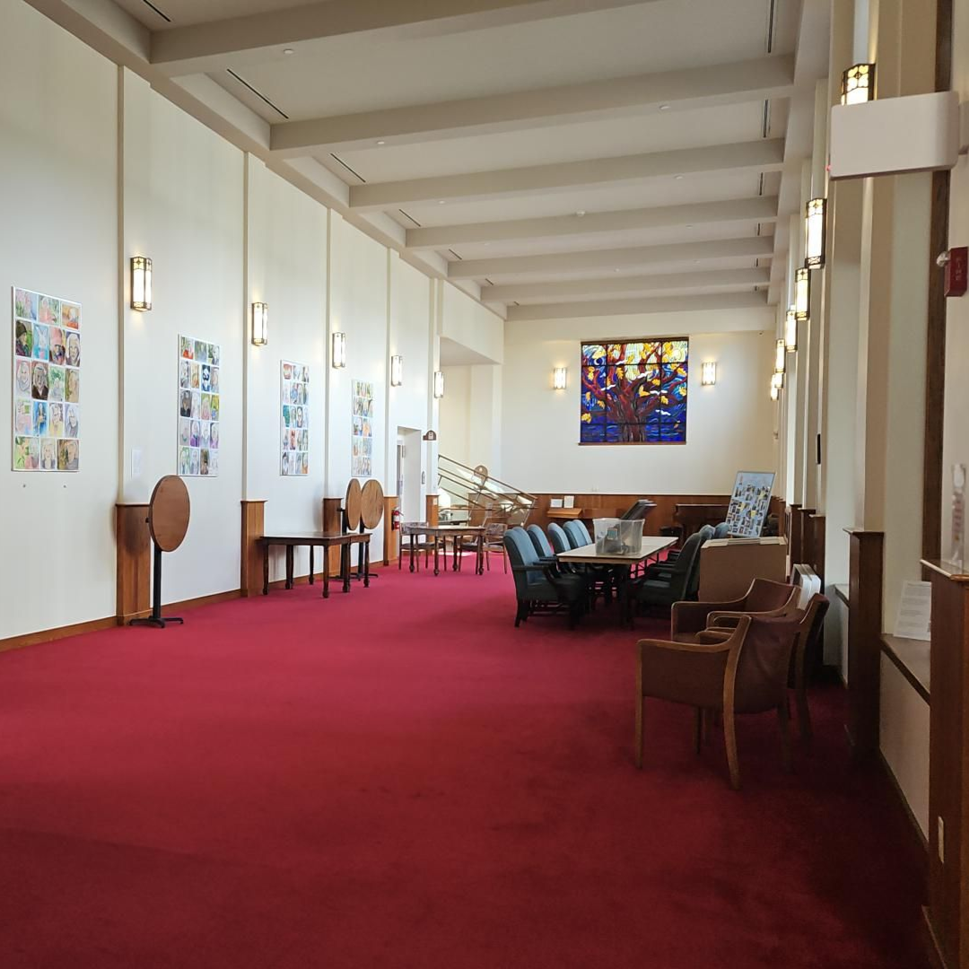Dim church interior with rows of chairs, central altar, and light from tall arched windows