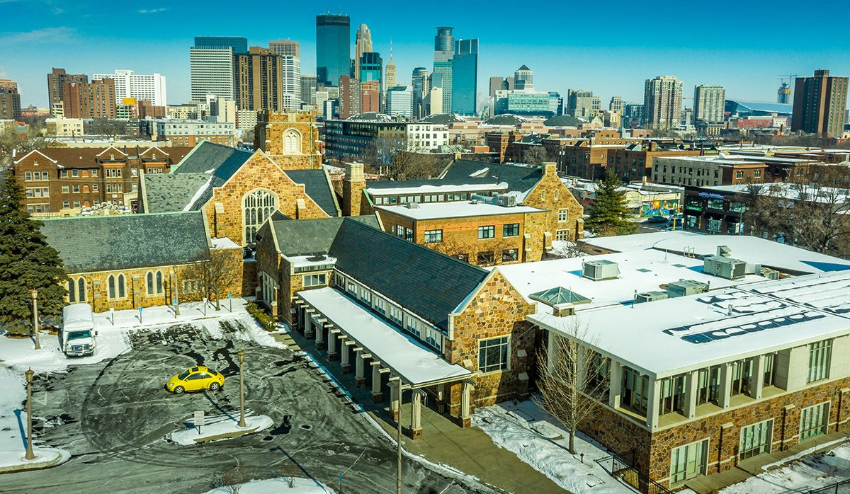 Snow-covered cityscape with historic brick buildings and modern skyscrapers under a clear blue sky.