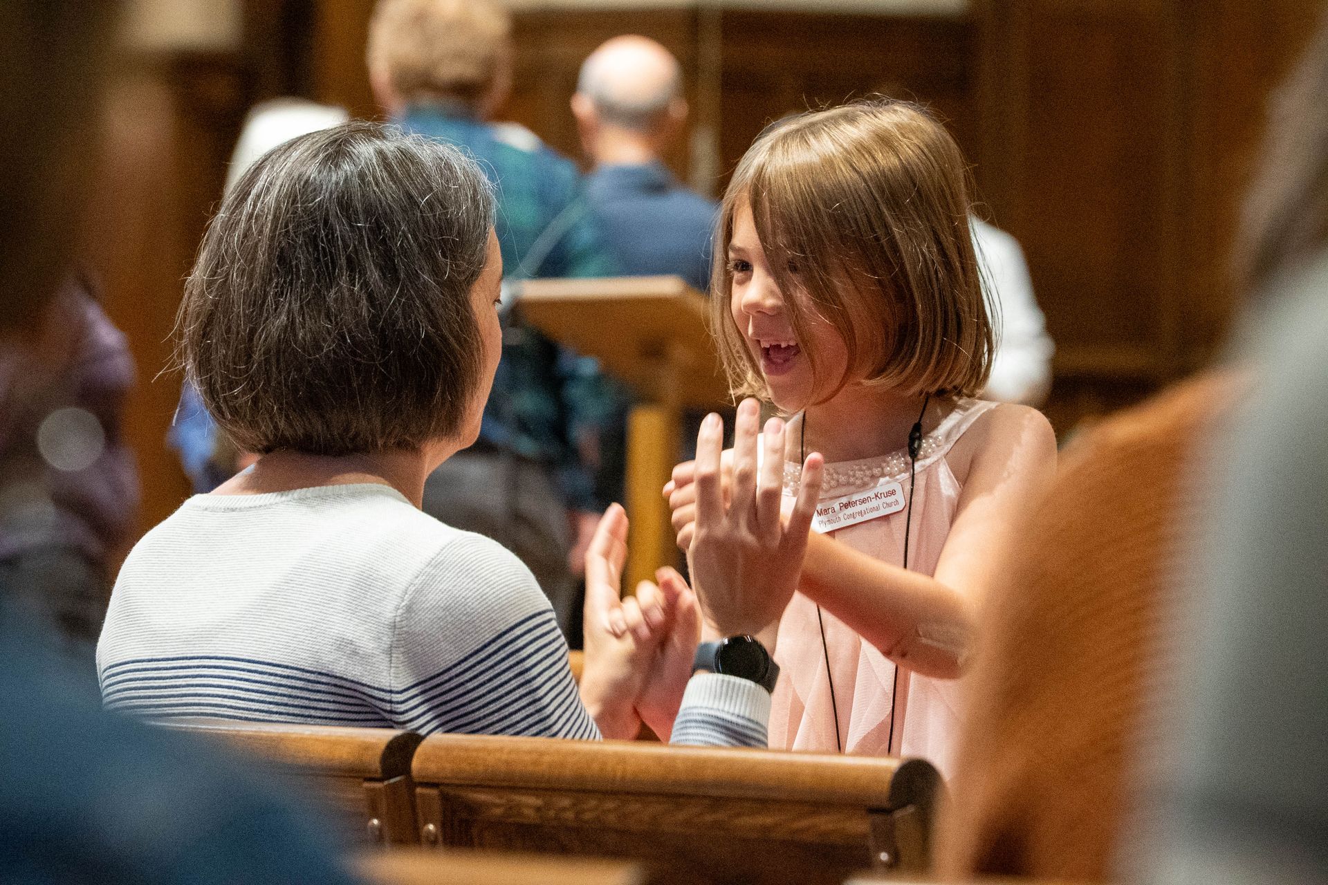 Two people seated indoors, smiling and chatting during a community gathering