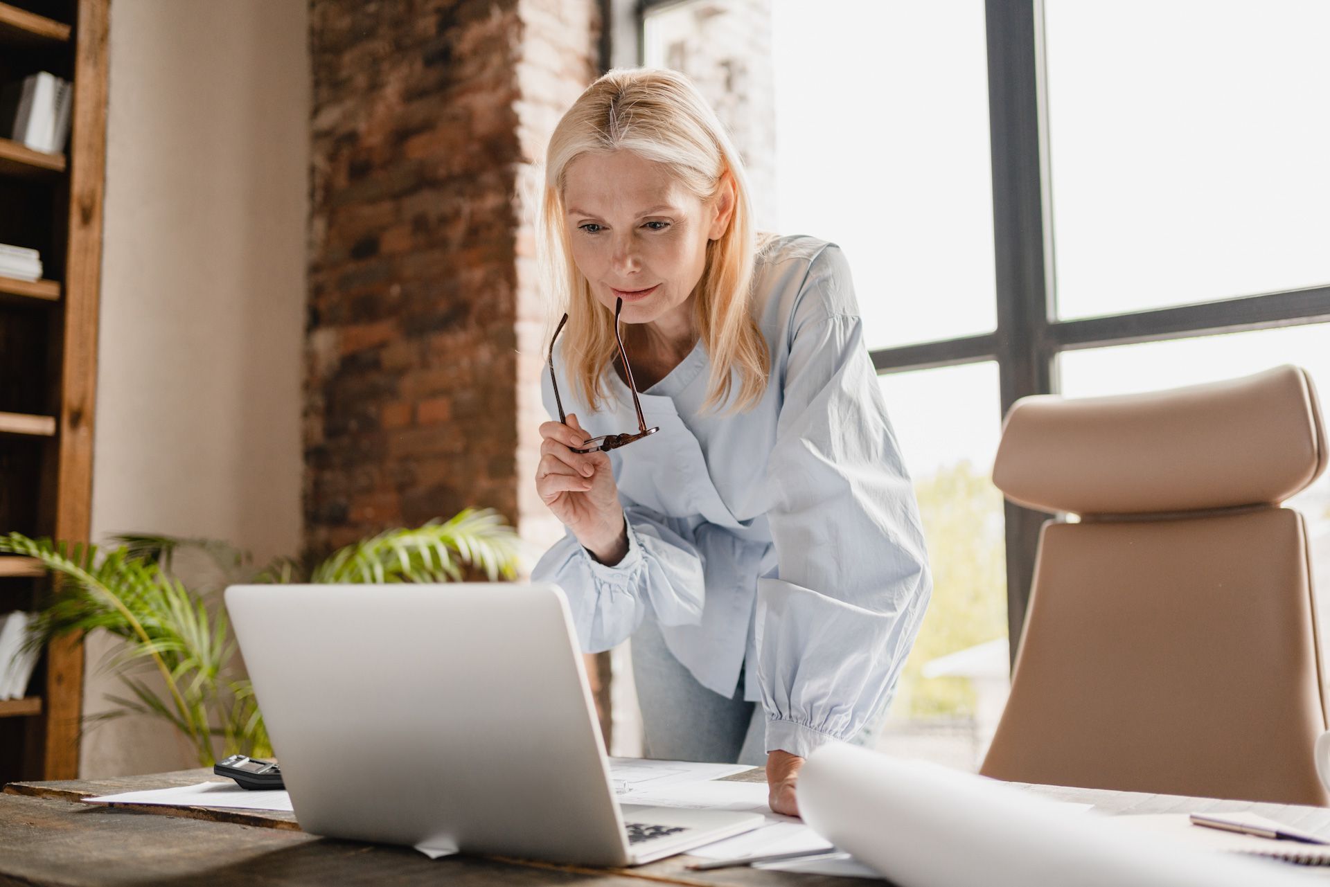 A woman is standing in front of a laptop computer.