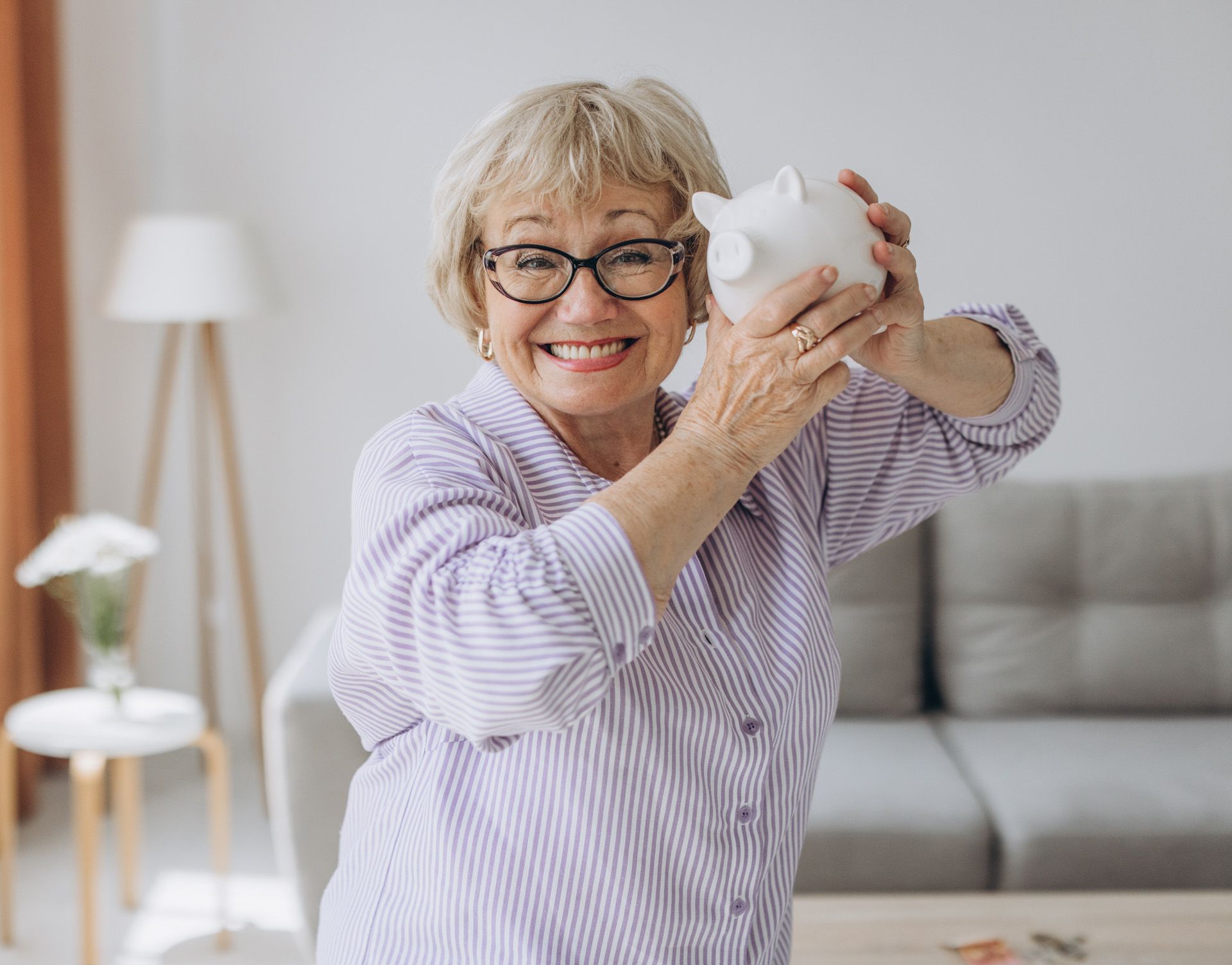 An elderly woman is holding a piggy bank in her hands.