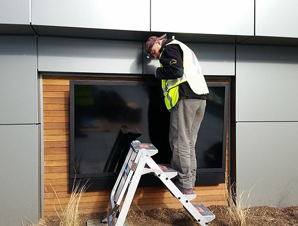Worker on a ladder inspecting a window on a modern building exterior