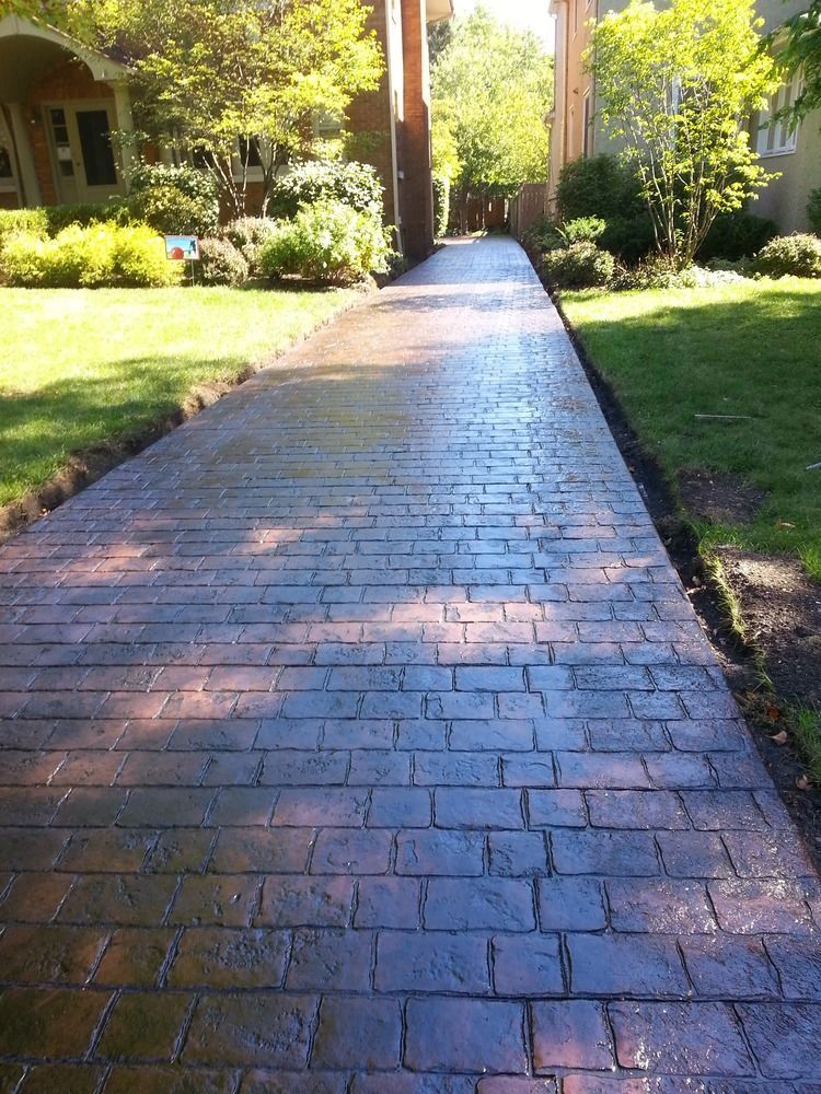 A brick walkway leading to a house in a residential area.