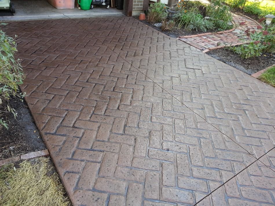 A brick walkway leading to a garage with a herringbone pattern.