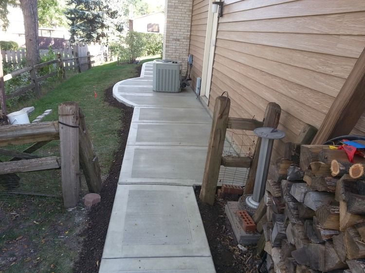 A concrete walkway leading to the side of a house