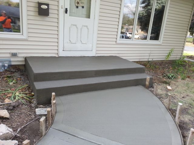 A concrete walkway is being built in front of a house