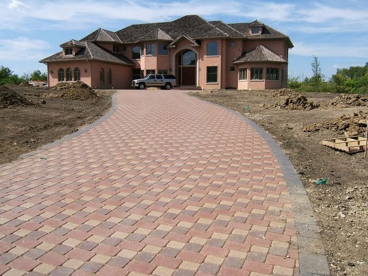 A brick driveway leading to a large house