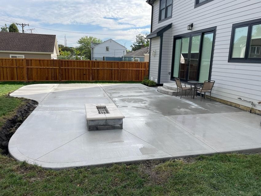 A patio with a fire pit in the backyard of a house.