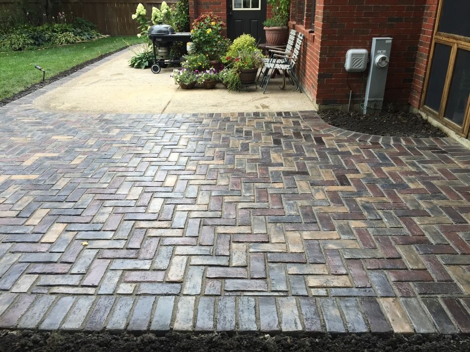 A brick patio with a grill and chairs in front of a brick house.