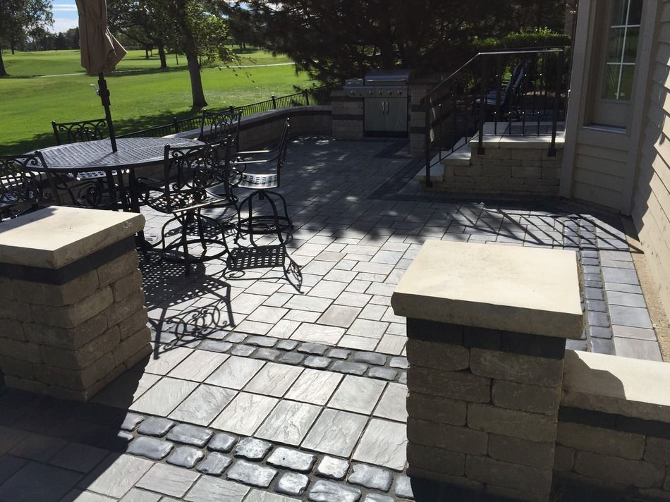 A patio with a table and chairs and a golf course in the background.