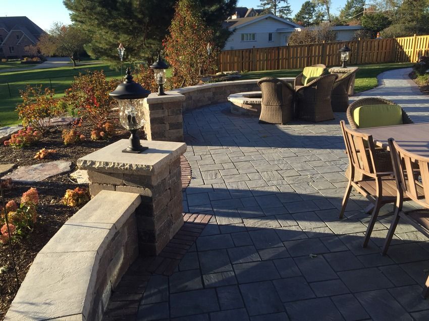 A patio with a table and chairs and a fence in the background