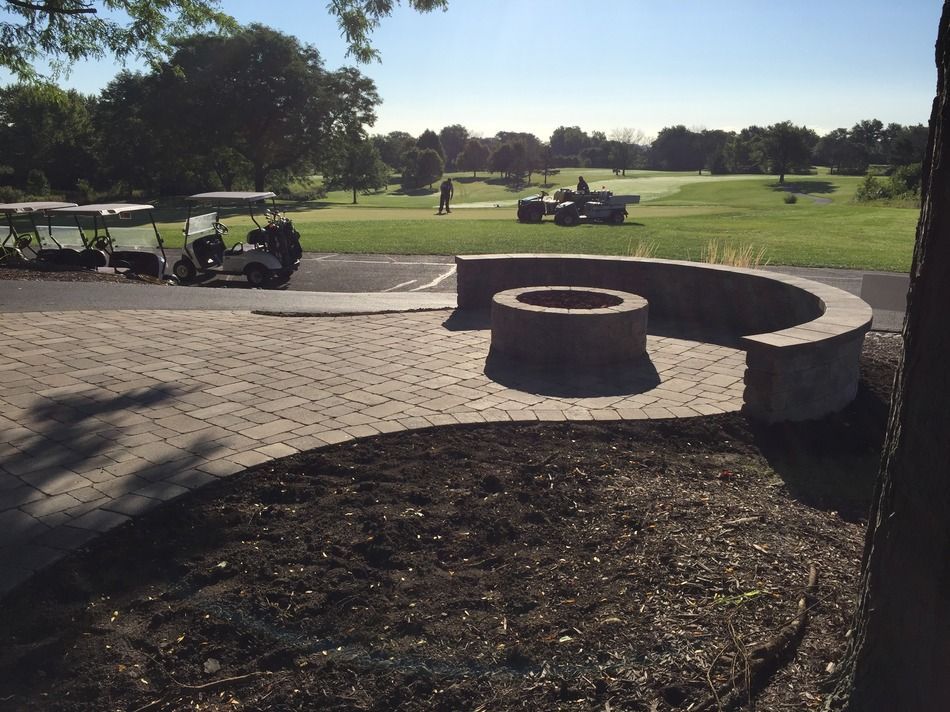 A golf cart is parked in front of a fire pit on a golf course.