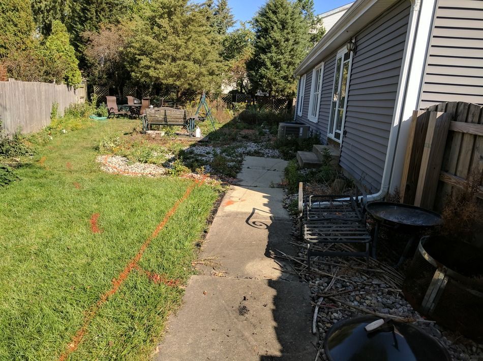 There is a concrete walkway leading to a house in the backyard.