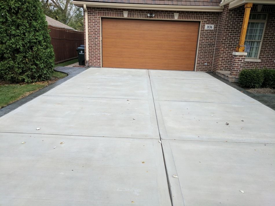 A brick house with a wooden garage door and a concrete driveway leading to it.