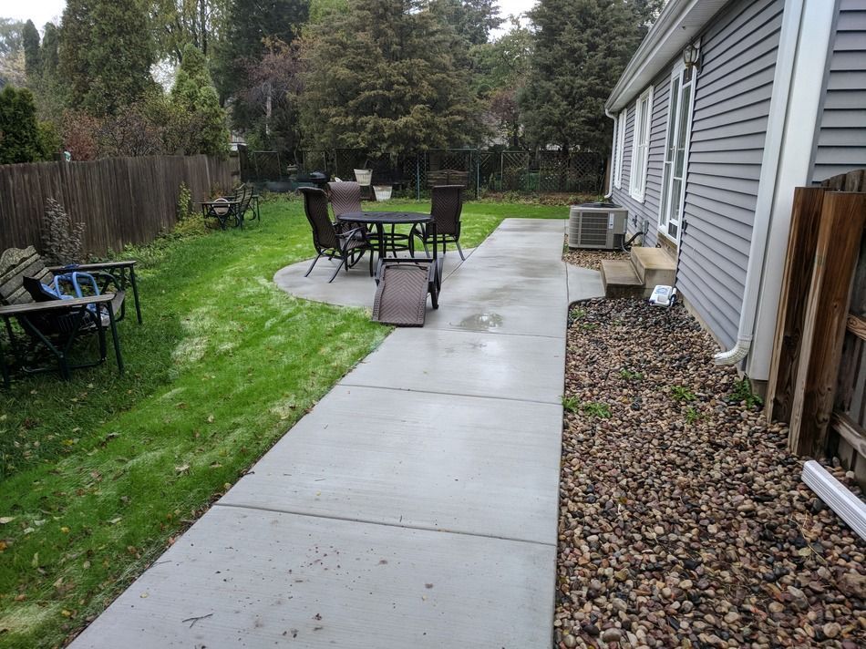 A patio with a table and chairs in the backyard of a house.