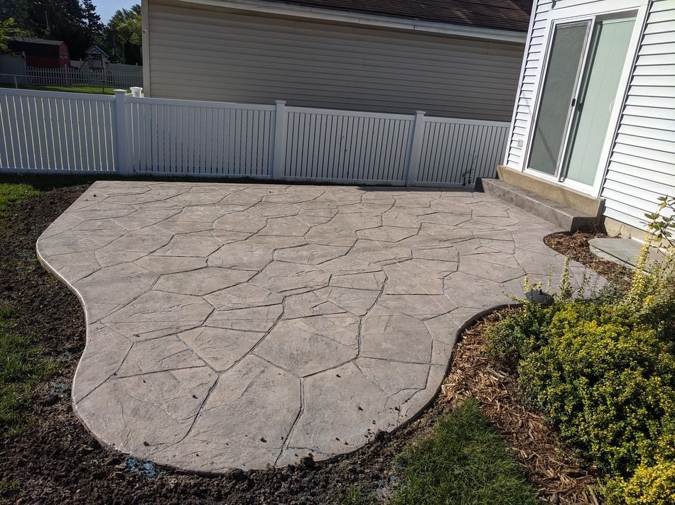 A patio with a white fence in the backyard of a house.