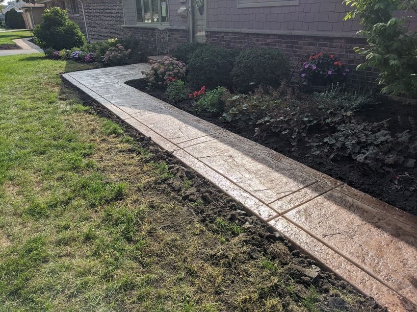 A concrete walkway is being built in front of a house.