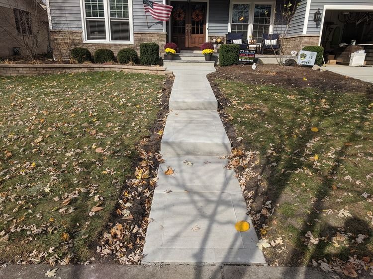 A concrete walkway leading to the front door of a house.