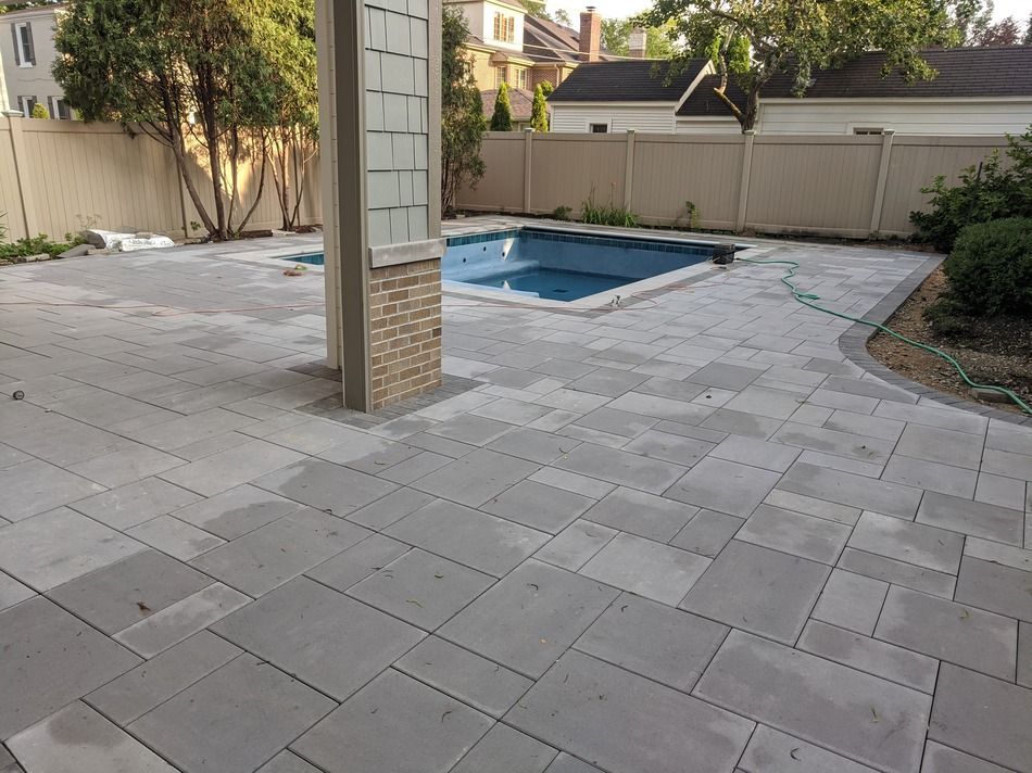 A patio with a swimming pool in the background