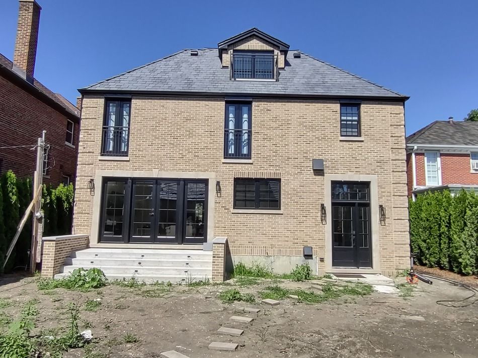 The back of a large brick house with black windows
