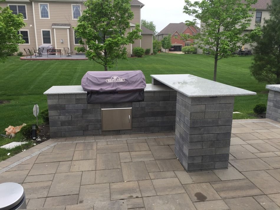 A grill is sitting on a brick patio in front of a house