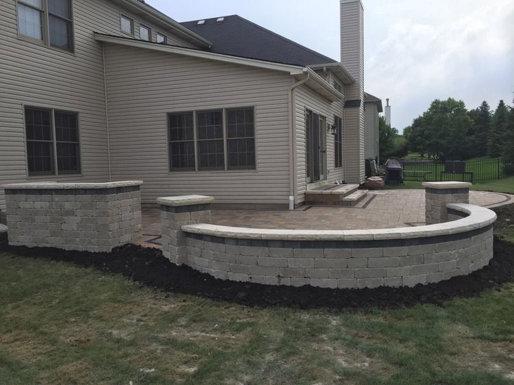 A house with a patio and a brick wall in front of it.