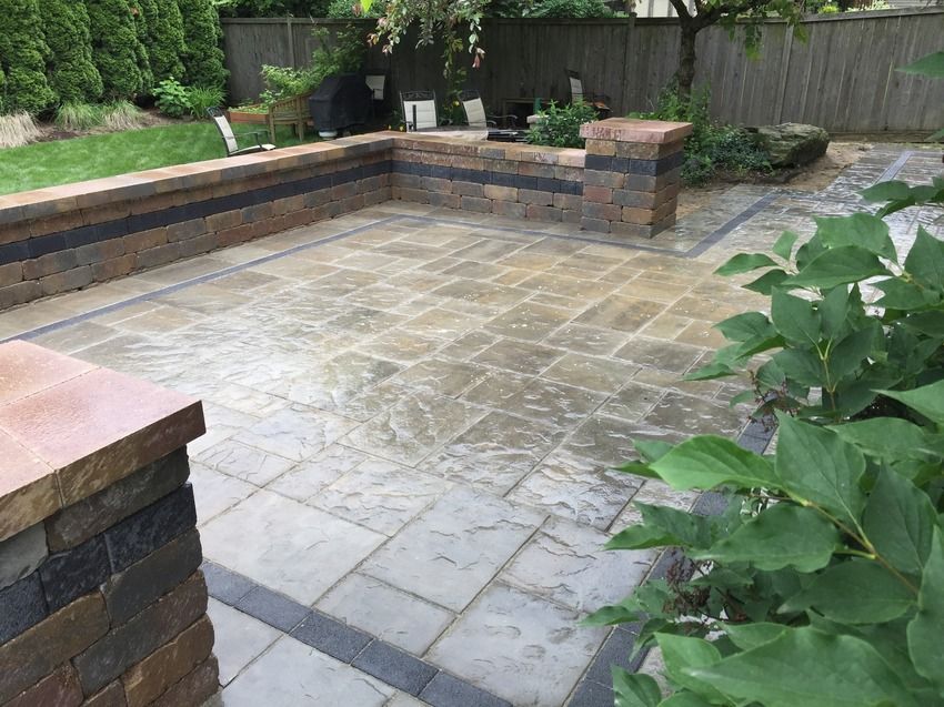 A patio with a brick wall and a fence in the background.