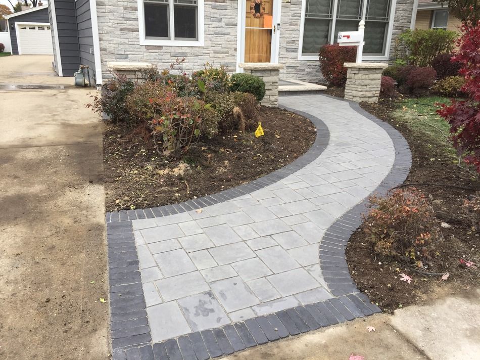 A brick walkway leading to the front of a house
