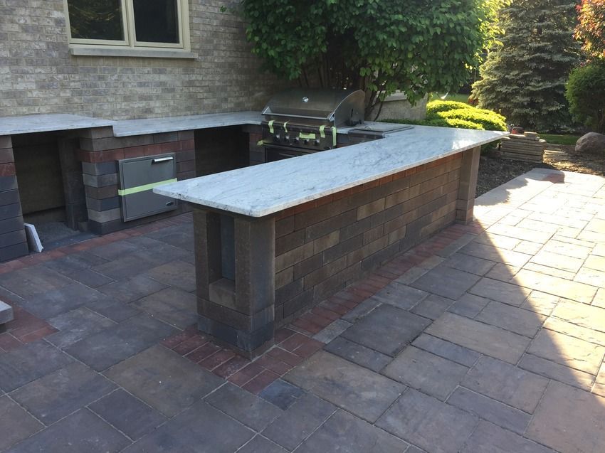 A brick patio with a grill and a marble counter top.