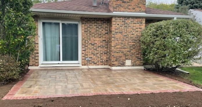 A brick house with a patio in front of it.