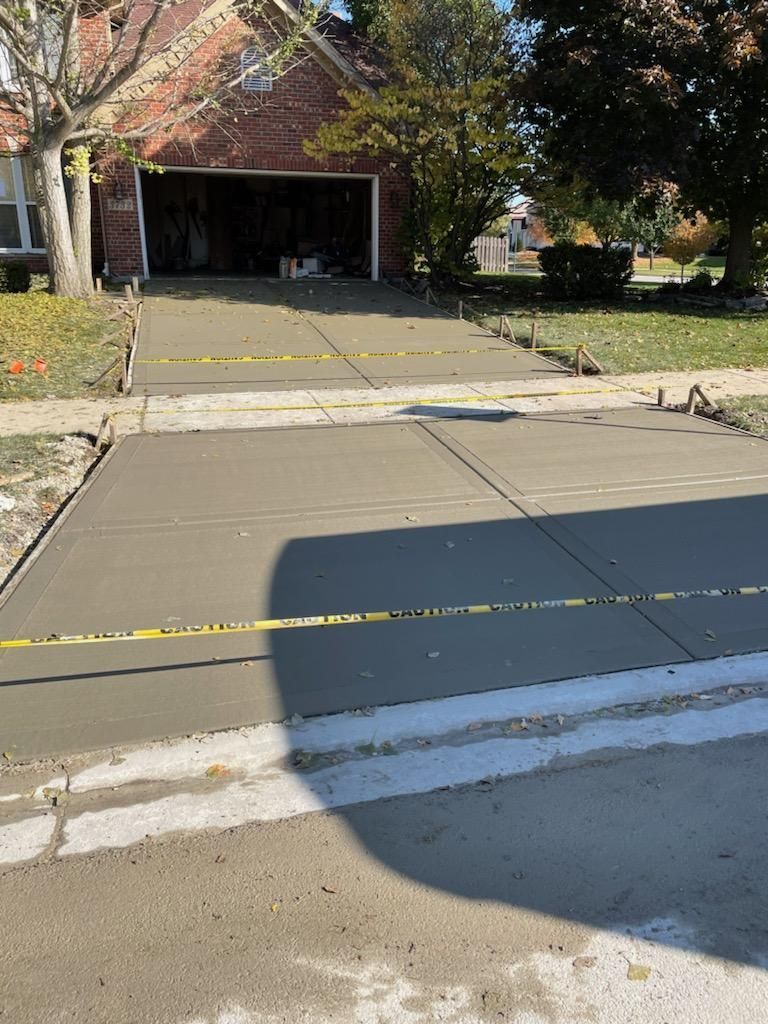 A concrete driveway is being built in front of a brick house.