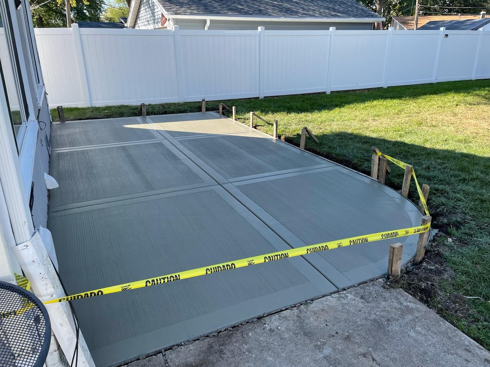 A concrete walkway is being built in the backyard of a house.