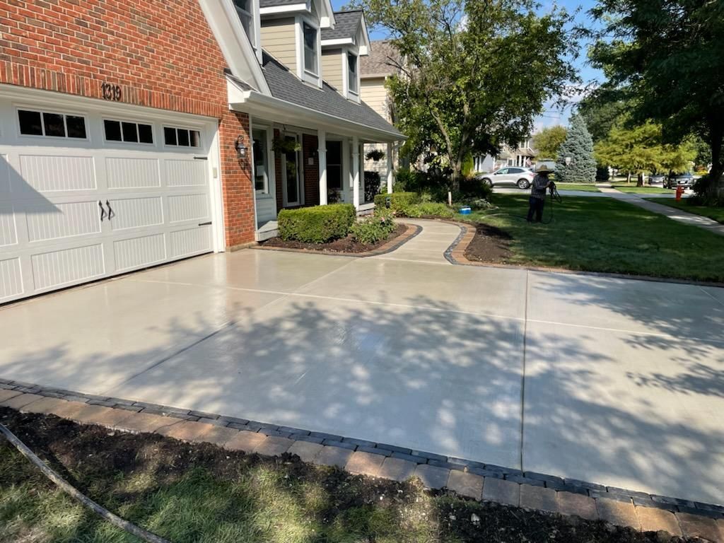 A brick house with a white garage door and a concrete driveway in front of it.