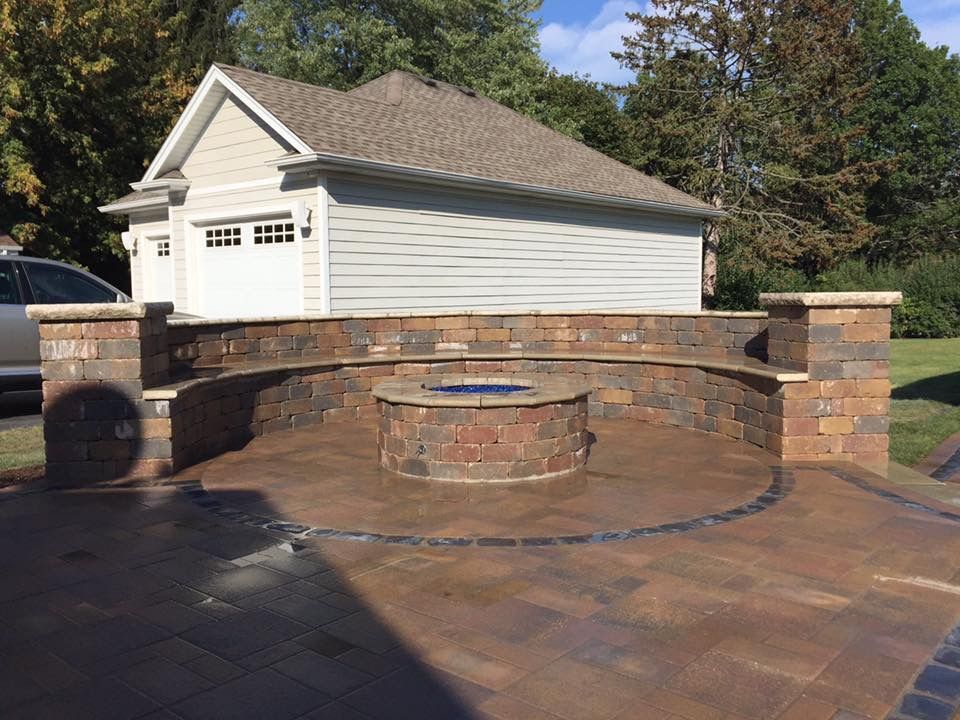 There is a fire pit in the middle of the patio in front of a garage.