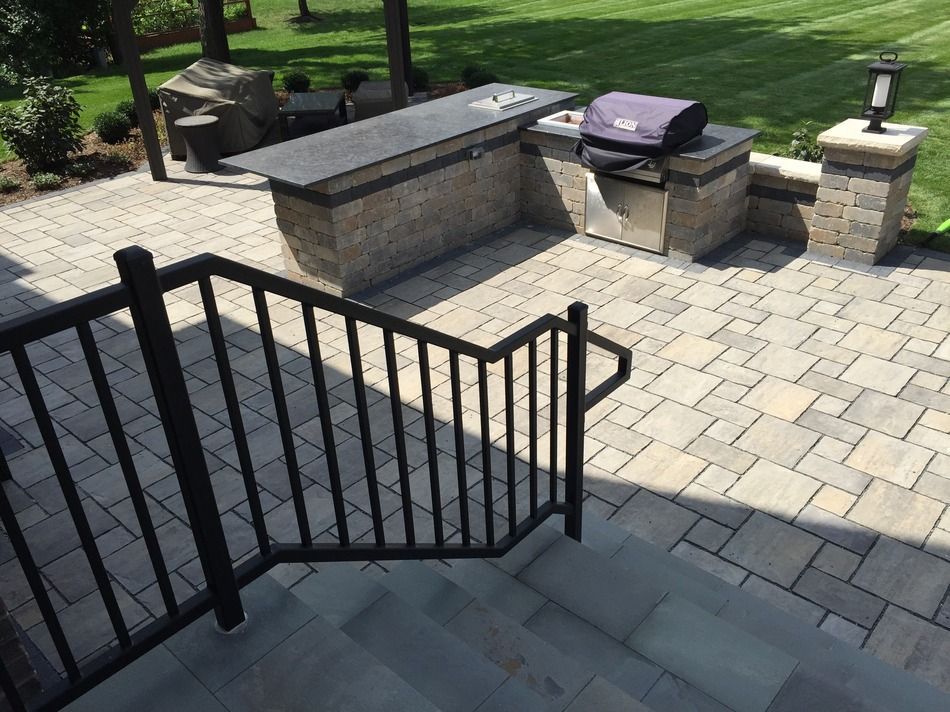 A patio with a grill and stairs leading up to it.