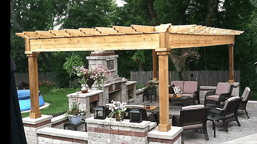 A patio with a wooden pergola and a fireplace