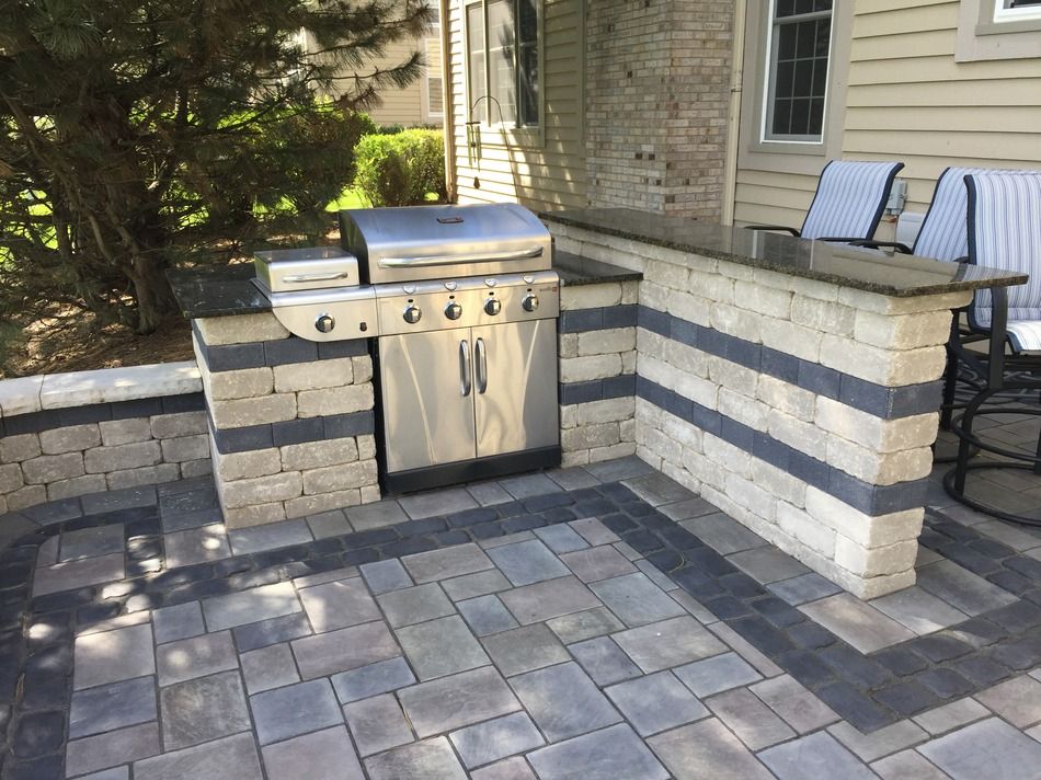 A grill is sitting on a patio next to a brick wall.