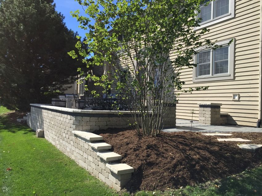 A house with a brick wall and stairs in front of it.