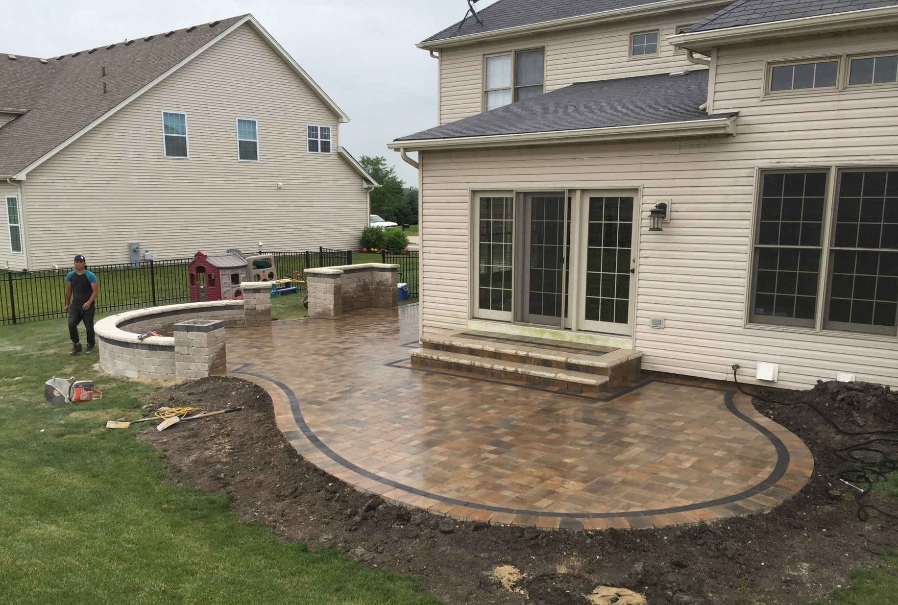 A man is standing in front of a house with a patio in front of it.