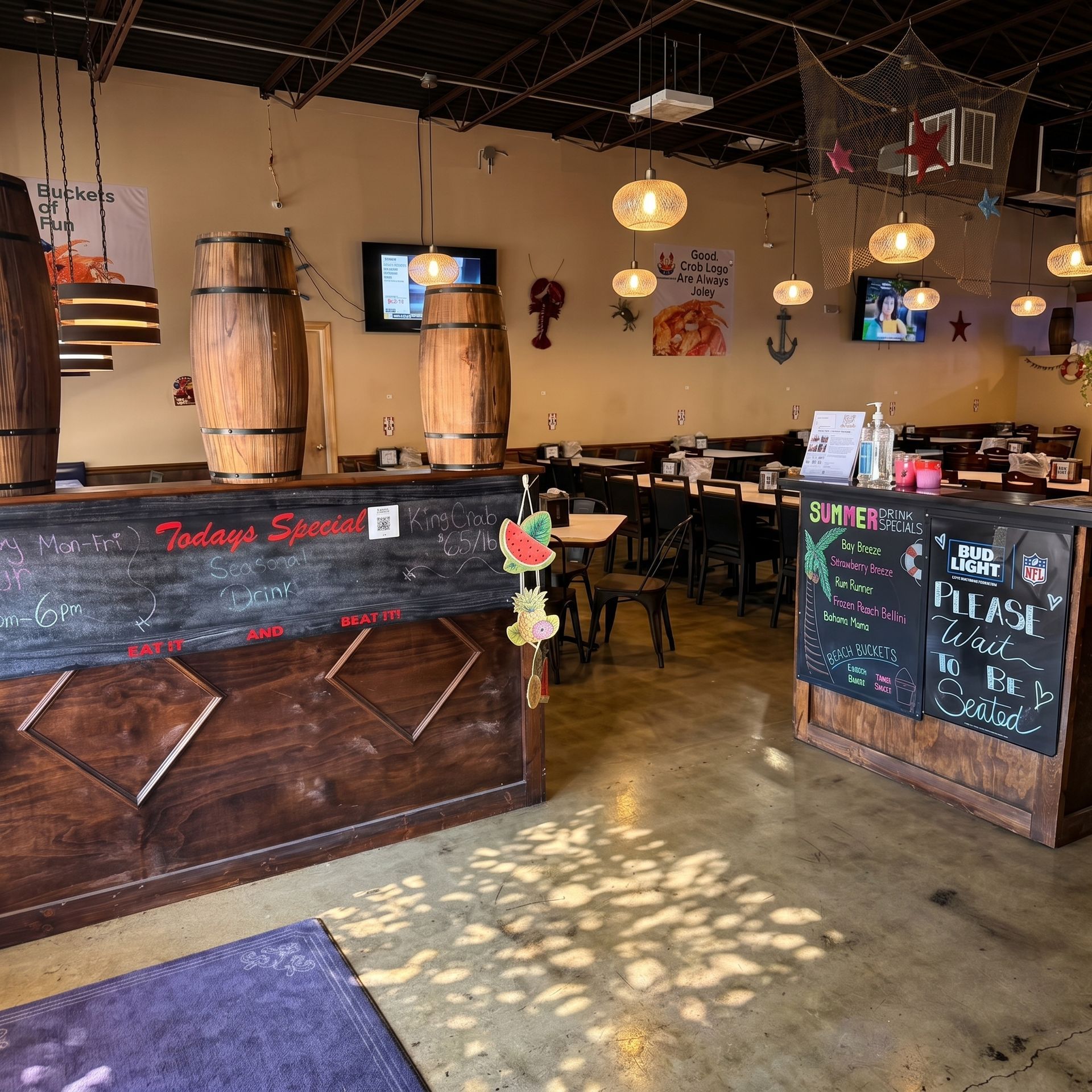 Rustic restaurant interior with wooden bar, chalkboard menu, hanging lights, and small tables.
