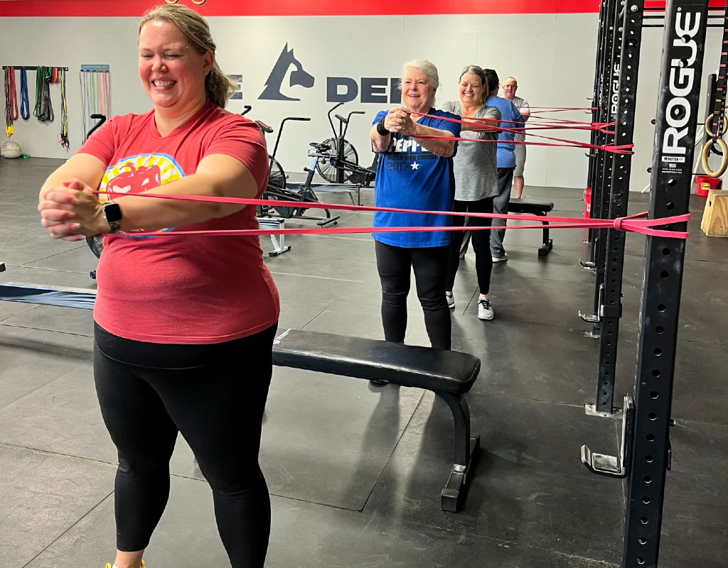 A group of women are doing exercises with resistance bands in a gym.