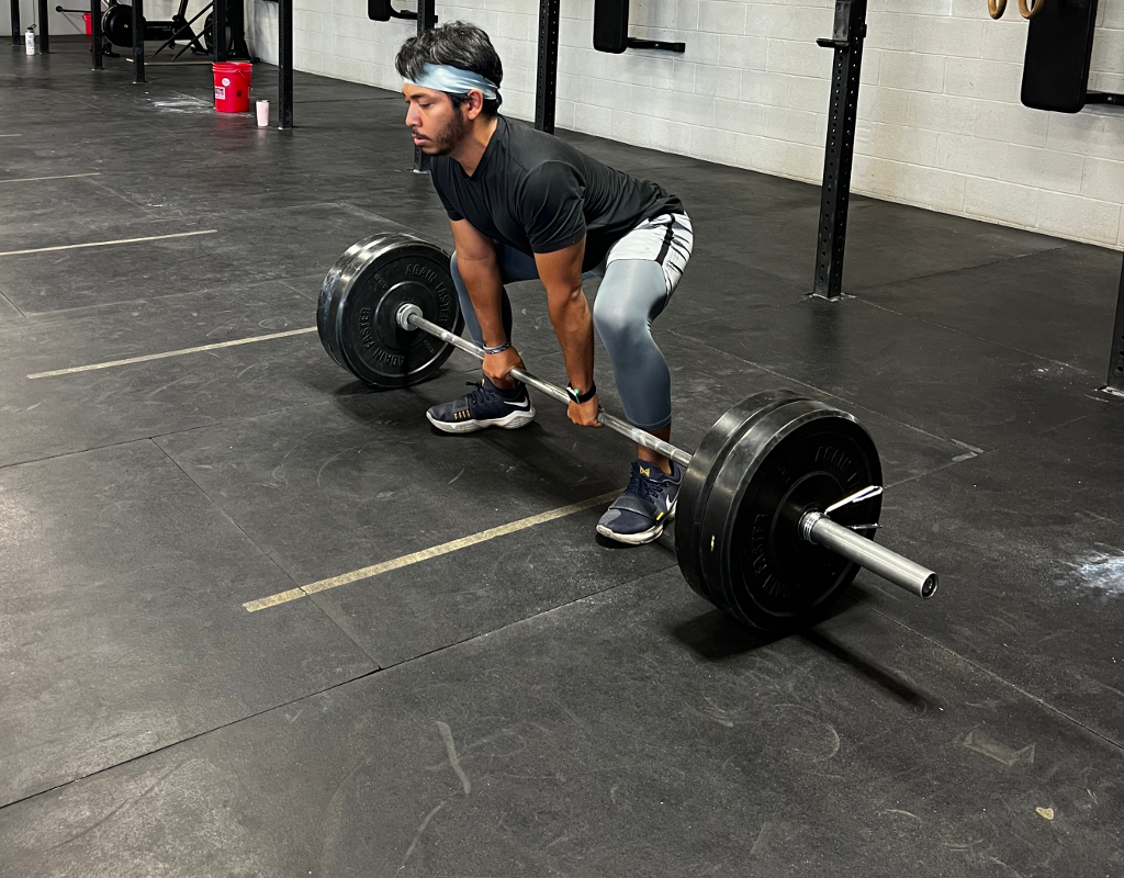 A man is lifting a barbell in a gym.