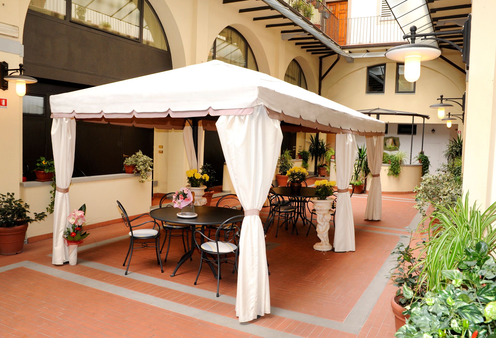 White canopy tent with tables and chairs in a sunlit courtyard courtyard
