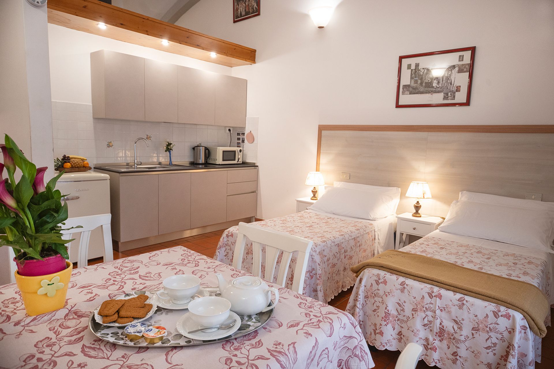 Cozy studio room with two twin beds, kitchenette, and breakfast tray on a floral tablecloth